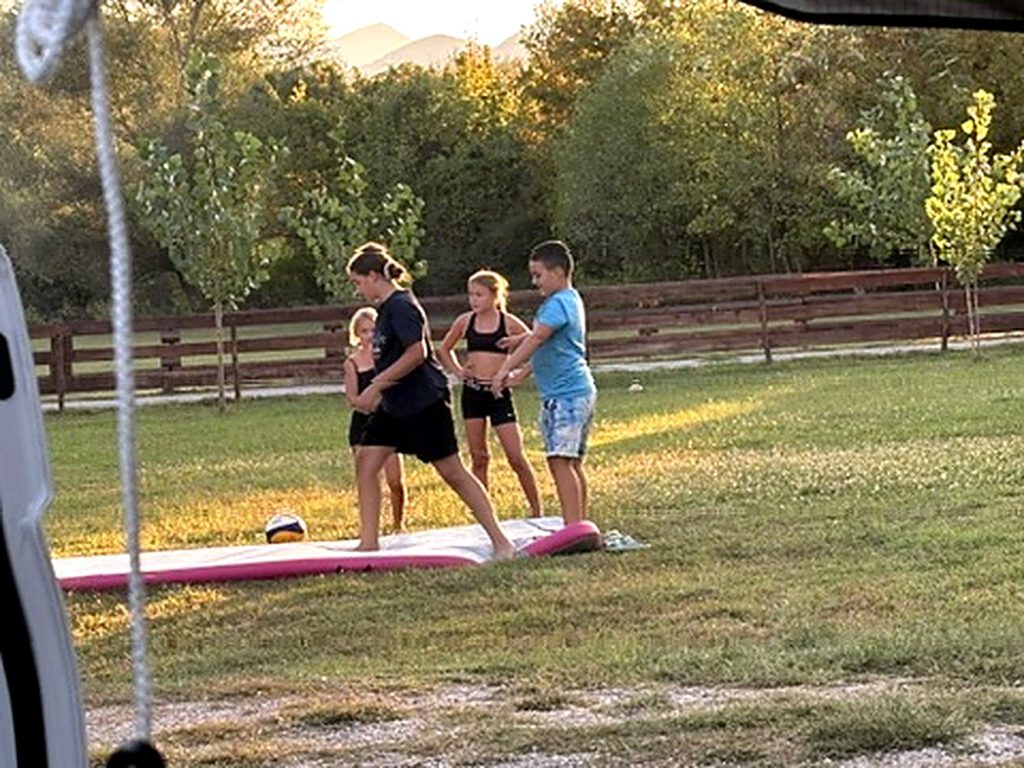 Familie beim Balance-Training auf dem SUP-Brett auf der Wiese