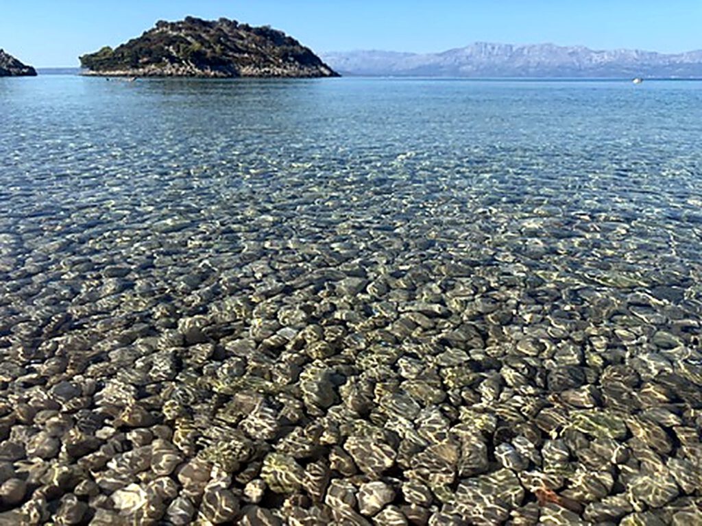 Glasklares Wasser ueber Kiesboden
