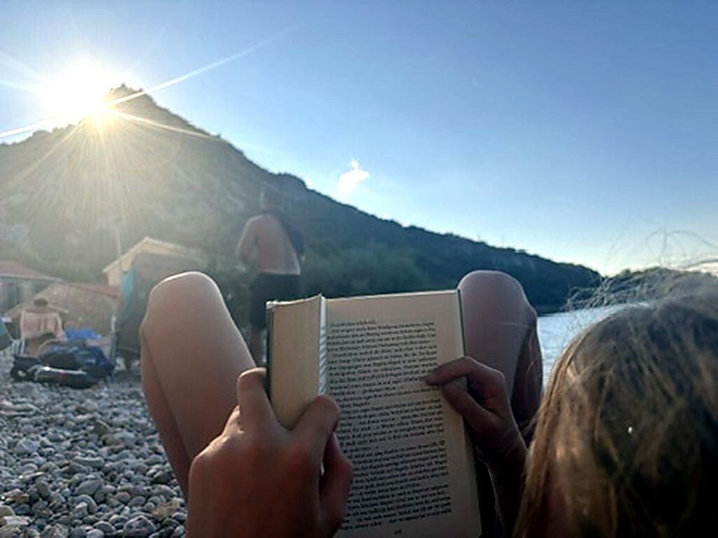 Lesen am Strand im Gegenlicht