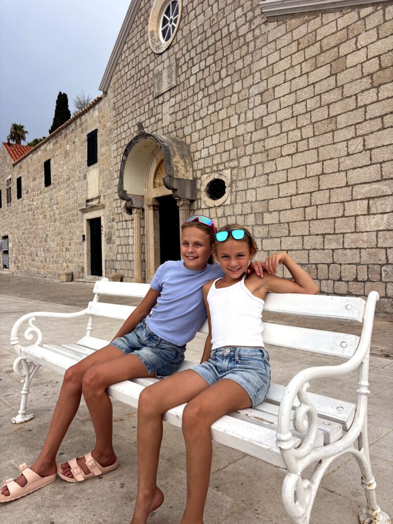 Zwei Mädchen auf einer weißen Bank in Cavtat