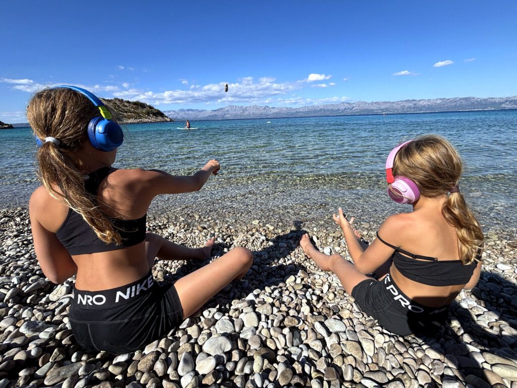 Maedchen mit Kopfhoerern am Kiesstrand
