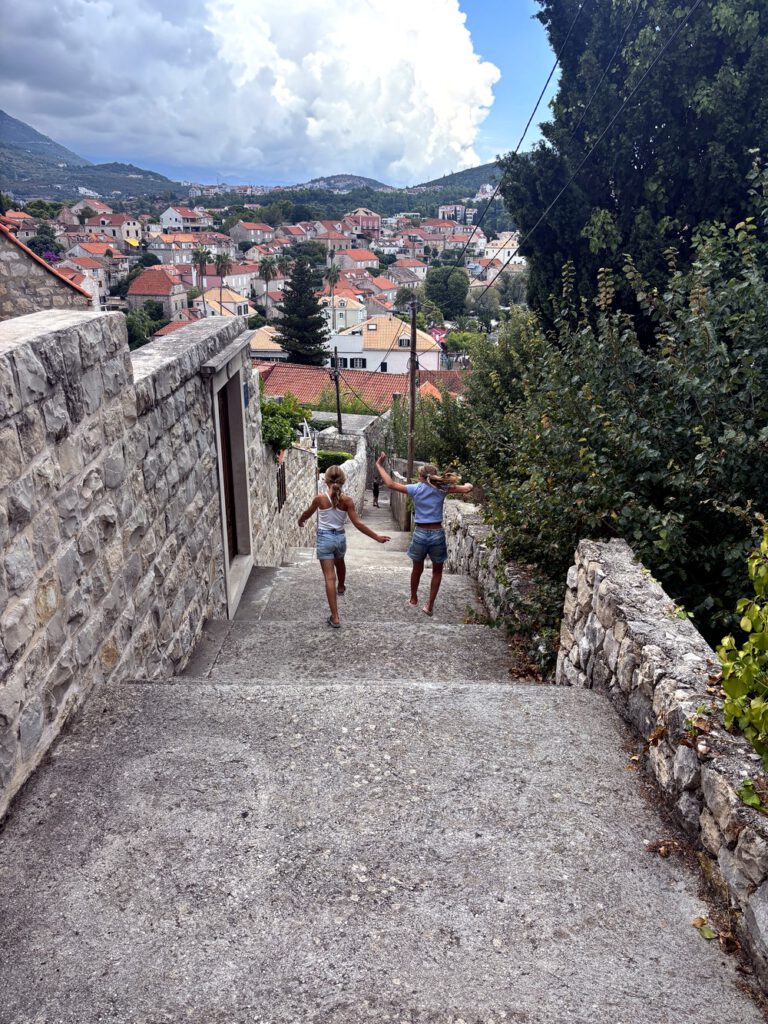 Mädchen springen die Treppe hinunter mit Blick auf Cavtat