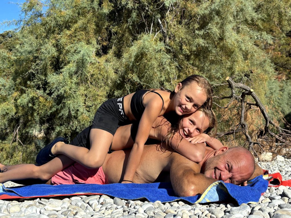 Papa mit den Toechtern am Strandtuch