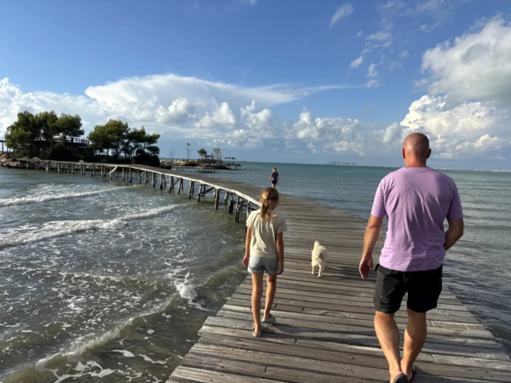Heiner, zwei Kinder und ein heller Hund spazieren über den gewundenen Holzsteg aufs Meer hinaus