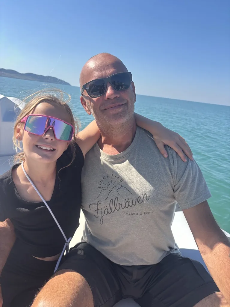 Heiner und eine Tochter mit pinker Sportbrille Arm in Arm beim Selfie im Boot