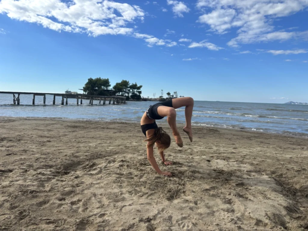 Ein Kind in der Brücke am Strand, dahinter Holzsteg und Insel