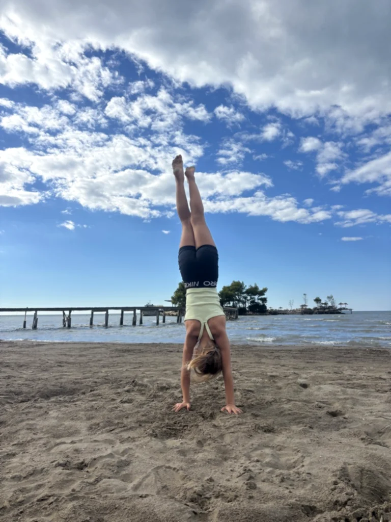 Ein Kind im Handstand vor blauem Himmel mit weißen Wolken