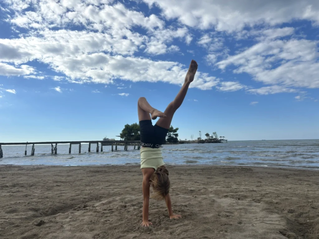 Ein Kind im Handstand mit angewinkeltem Bein, dahinter Steg und Insel