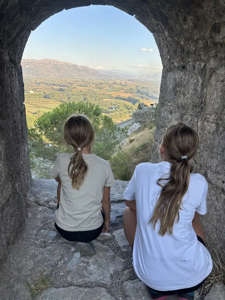 Kinder blicken durch einen Torbogen der Burg Rozafa