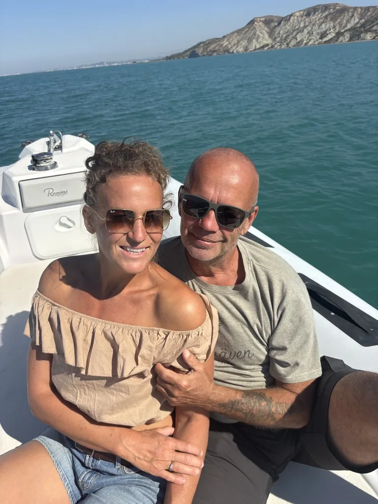 Lisa und Heiner beim Selfie vorne im Schlauchboot, im Hintergrund eine helle Steilküste