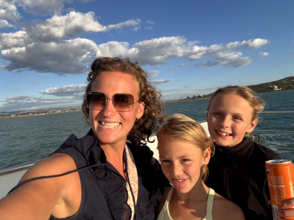 Lisa mit Sonnenbrille macht ein Selfie mit zwei lachenden Kindern auf dem Boot