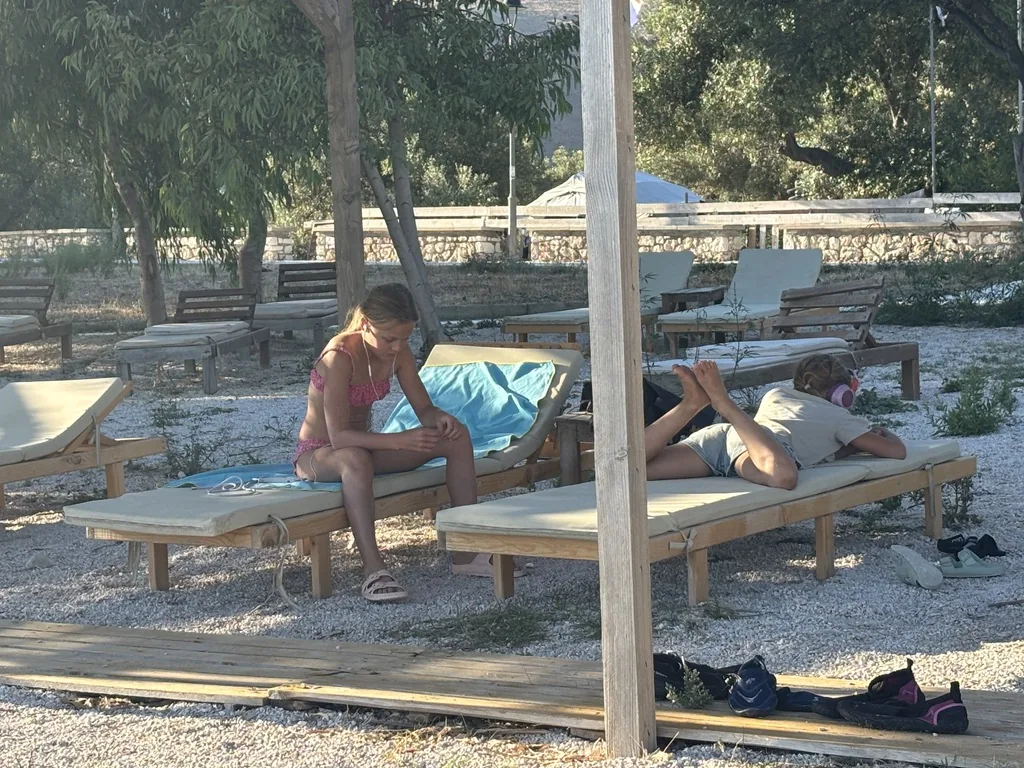 Die beiden Mädchen entspannen auf Strandliegen, eine mit pinken Kopfhörern