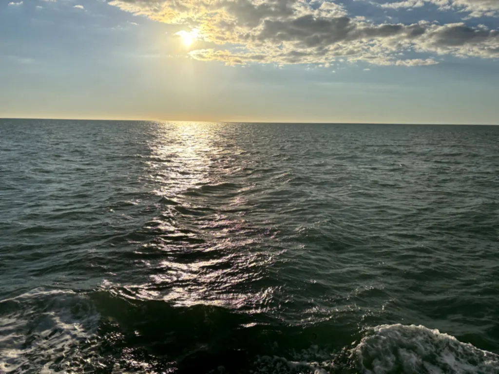 Die tief stehende Sonne glitzert auf dem Meer hinter dem Boot
