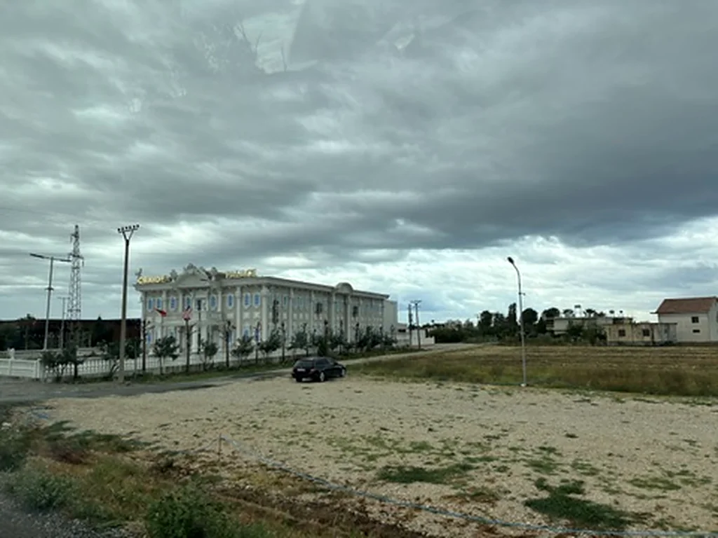 Riesiges weißes Gebäude im Palaststil neben einem leeren Schotterplatz unter Gewitterwolken