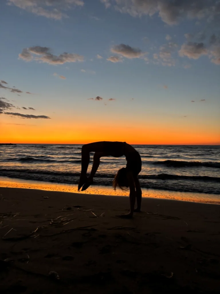 Silhouette eines Kindes in der Brücke am Strand vor leuchtend orangem Himmel