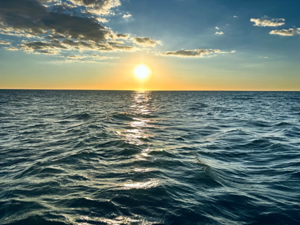 Die Sonne steht knapp über dem Horizont und spiegelt sich in den Wellen