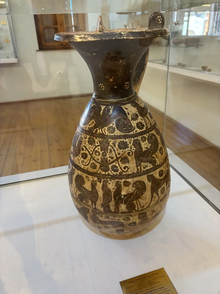Bemalte antike Kanne mit schwarzfigurigen Tierfriesen in einer Vitrine des Museums